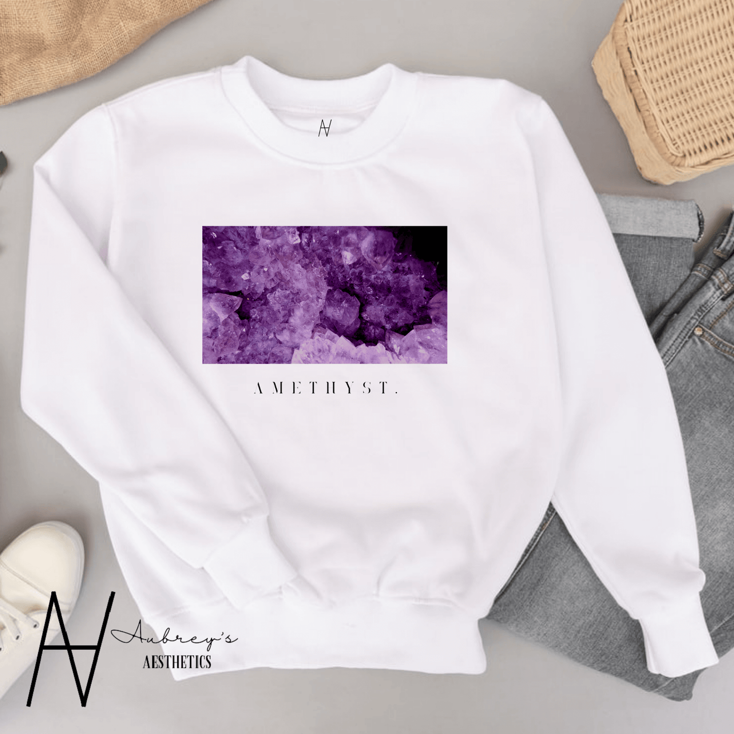 A white crewneck sweatshirt laid flat with a rectangular purple amethyst crystal print on the front.